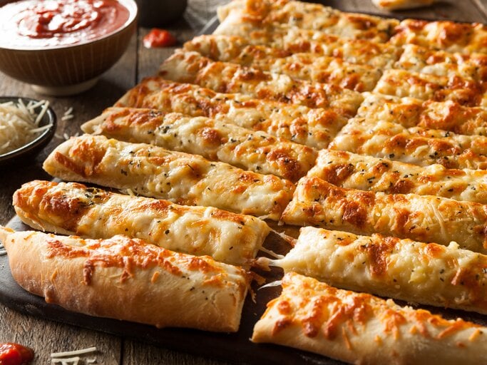 Blech mit in Stangen geschnittene Käse-Pizza umrundet von den Zutaten. | © Getty Images/bhofack2