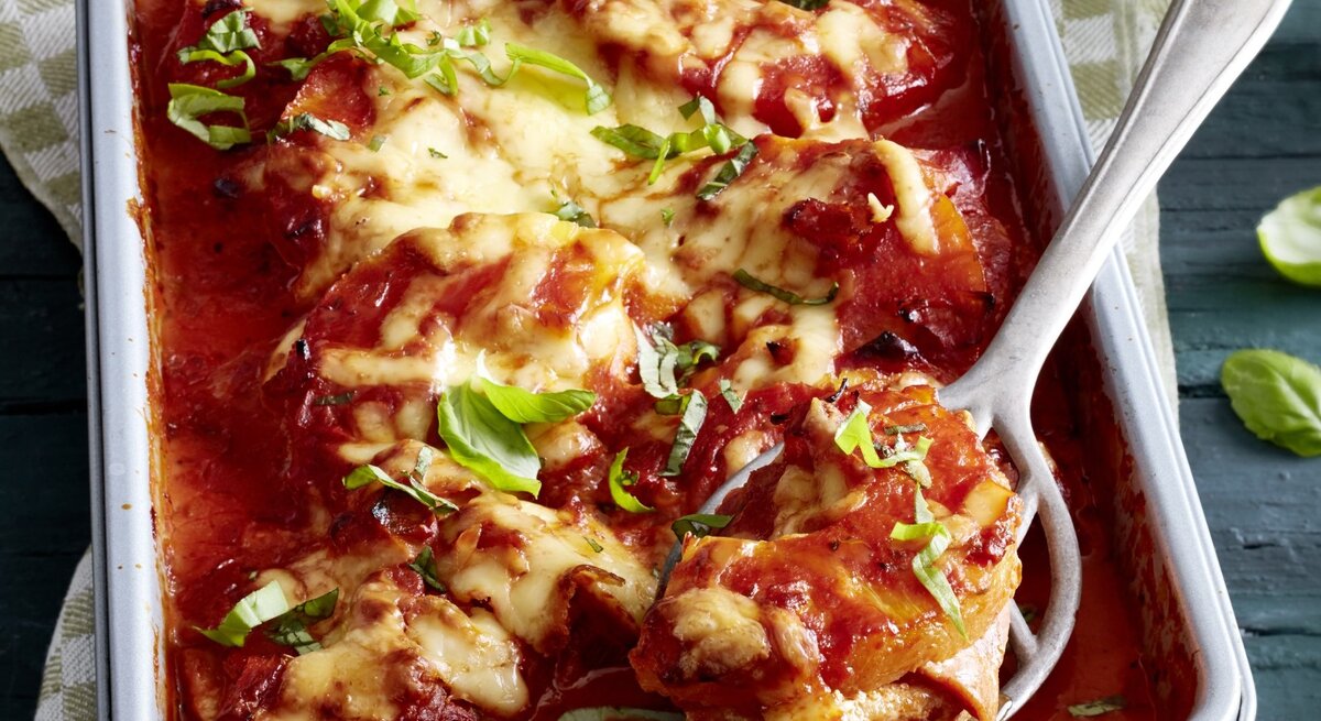 In einer Auflaufform ist eine Portion Schnitzel-Pizza Hawaii angerichtet. SIe ist mit Käse überbacken und sieht cremig aus.