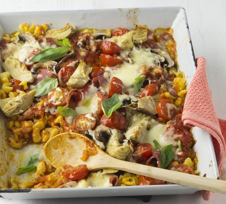 Überbackene Pizza-Spätzle mit Pilzen, Salami und Tomatensoße in einer quadratischen weißen Auflaufform.  | © StockFood / StockFood Studios / Lehmann, Joerg