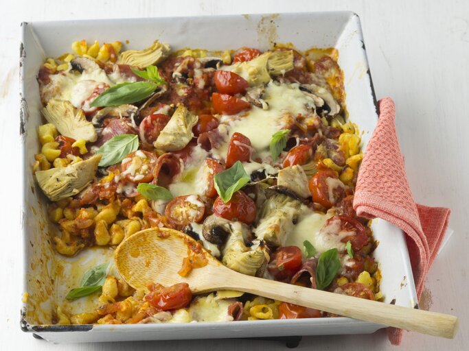 Überbackene Pizza-Spätzle mit Pilzen, Salami und Tomatensoße in einer quadratischen weißen Auflaufform.  | © StockFood / StockFood Studios / Lehmann, Joerg