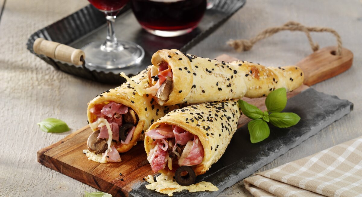 Drei Pizza-Hörnchen mit Schinken serviert.