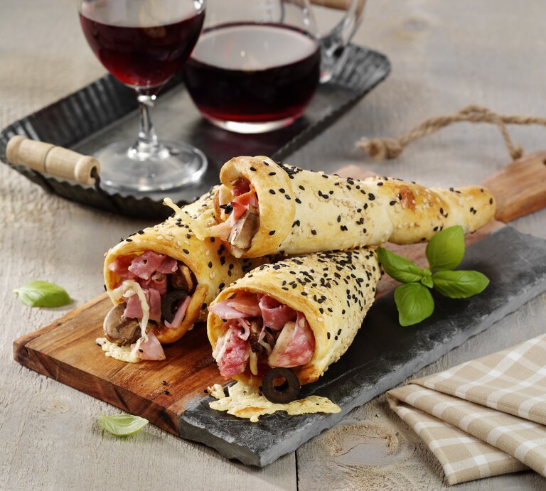 Drei Pizza-Hörnchen mit Schinken serviert. | © StockFood/ StockFood Studios/ Photoart