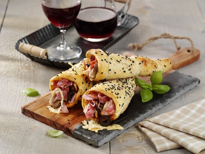 Drei Pizza-Hörnchen mit Schinken serviert. | © StockFood/ StockFood Studios/ Photoart