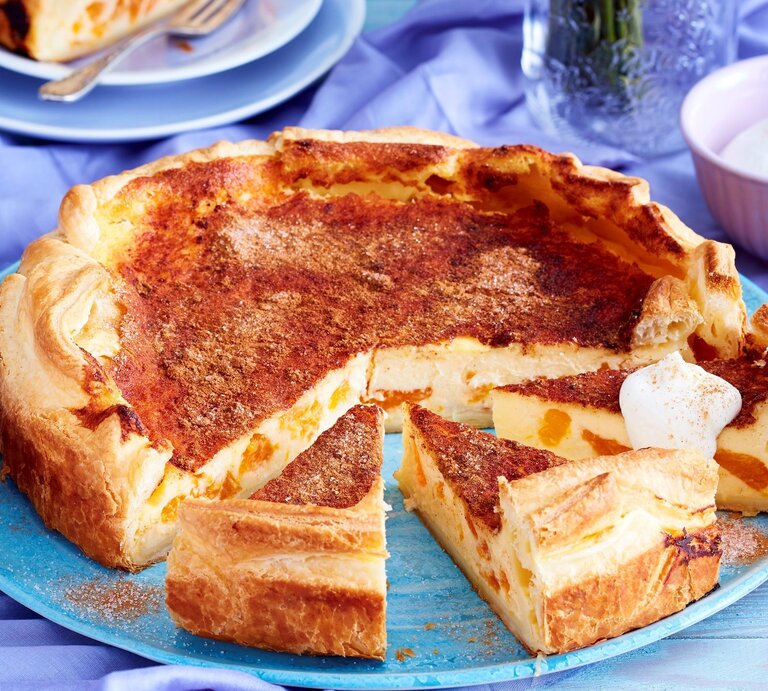 Auf einem blauen Teller liegt ein Blätterteig-Schmand-Kuchen. Er ist mit einem Klecks Sahne bedeckt. | © EAT CLUB / Isabell Triemer