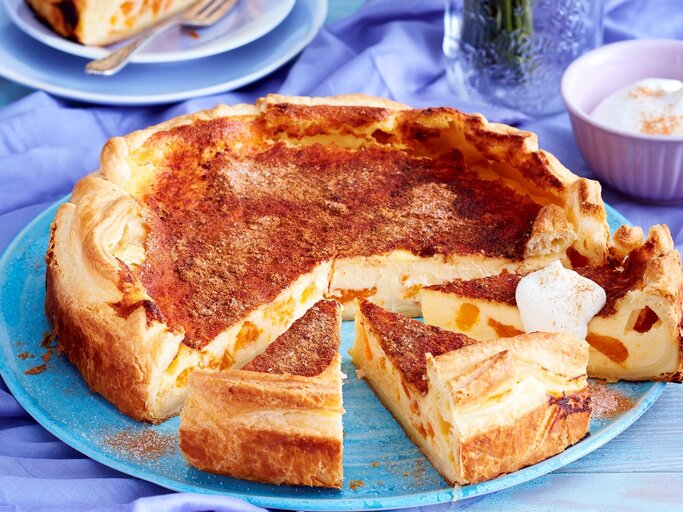 Auf einem blauen Teller liegt ein Blätterteig-Schmand-Kuchen. Er ist mit einem Klecks Sahne bedeckt. | © EAT CLUB / Isabell Triemer