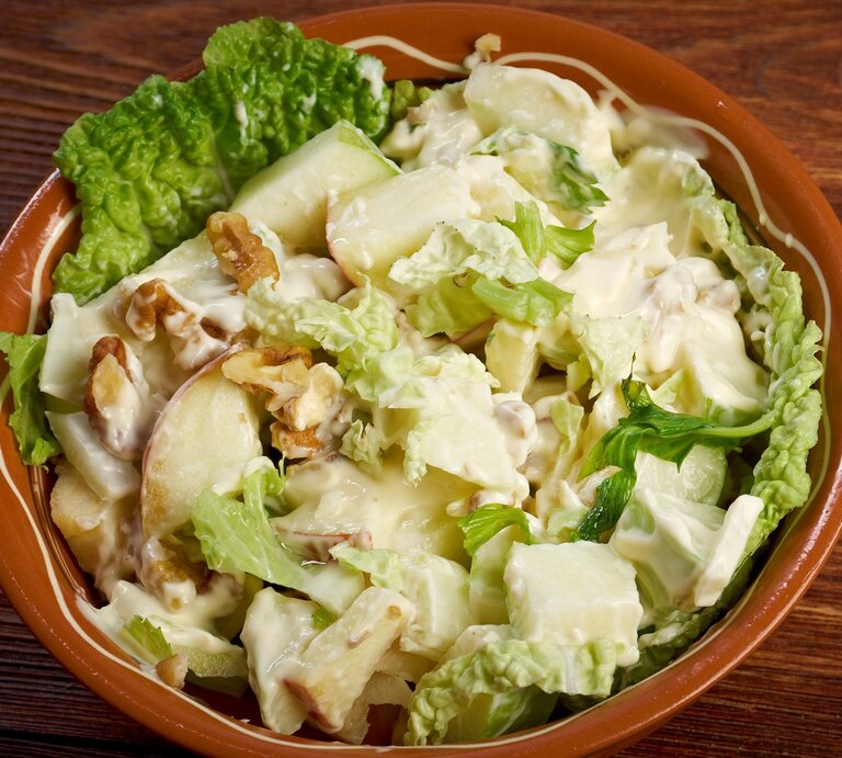 Eine braune Schale mit dem Salat auf einem dunklen Holztisch von oben fotografiert. | © Shutterstock/ Fanfo