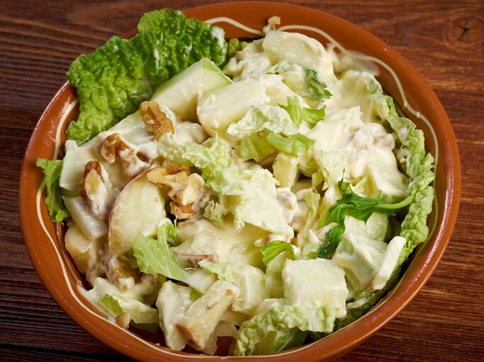 Eine braune Schale mit dem Salat auf einem dunklen Holztisch von oben fotografiert. | © Shutterstock/ Fanfo