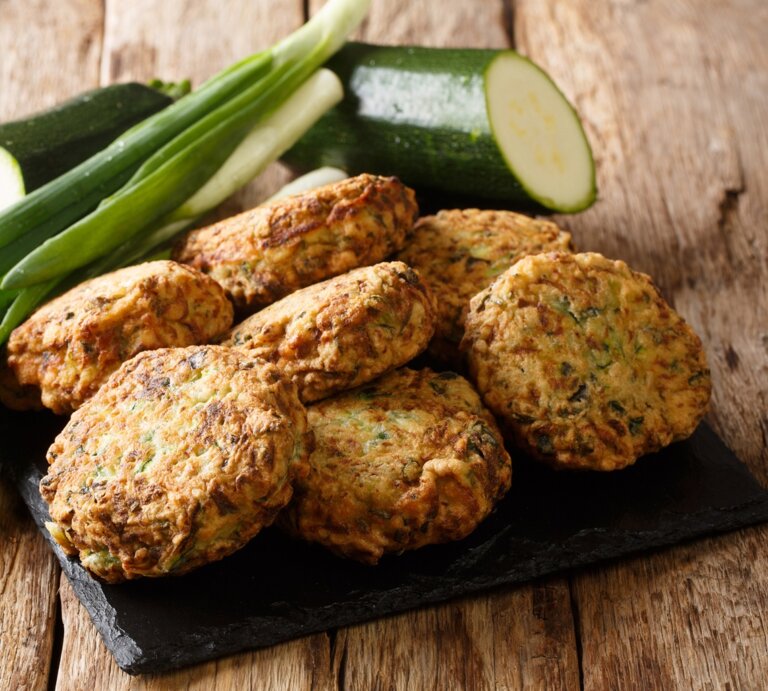 Eine schwarze Schieferplatte mit Zucchini-Feta-Kugeln oben drauf. | © GettyImages/ALLEKO