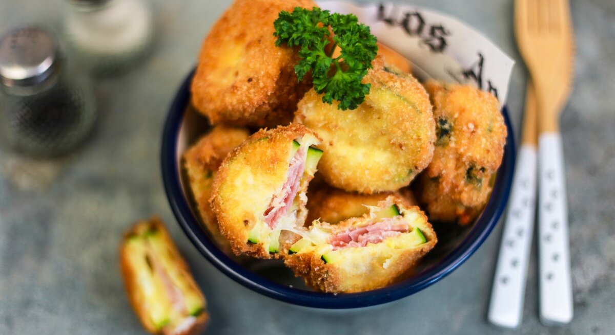 Cordon bleu mit Zucchini, Mozzarella und Schinken, angeschnitten serviert in einer großen Schale und garniert mit frischer Petersilie. 