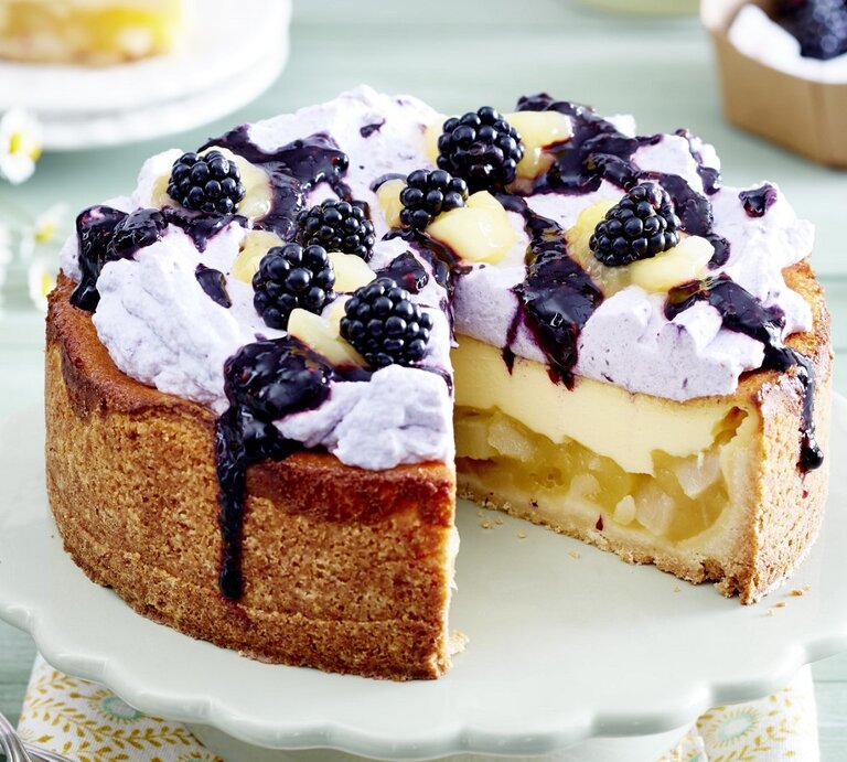 Auf einem Teller steht eine Birnen-Brombeer-Schmandtorte. Sie ist mit einer lila Creme verziert und mit Früchten bedeckt. Darüber wurde eine Brombeersoße gegeben.  | © EAT CLUB / Isabell Triemer