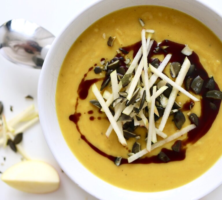 Kürbis-Apfel-Suppe mit Curry in einer Schüssel, dekoriert mit Samen und Kernen, von oben fotografiert. | © Nadine Hüttenrauch