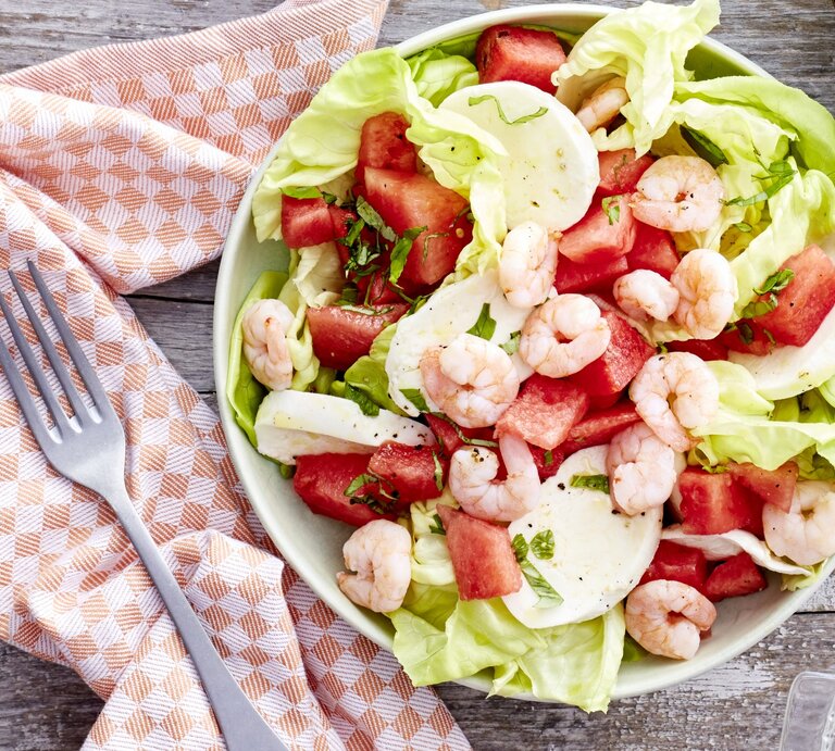 In einer Schüssel ist ein Wassermelonen-Salat mit Mozzarella angerichtet. Er ist mit Garnelen garniert. | © EAT CLUB / Isabell Triemer