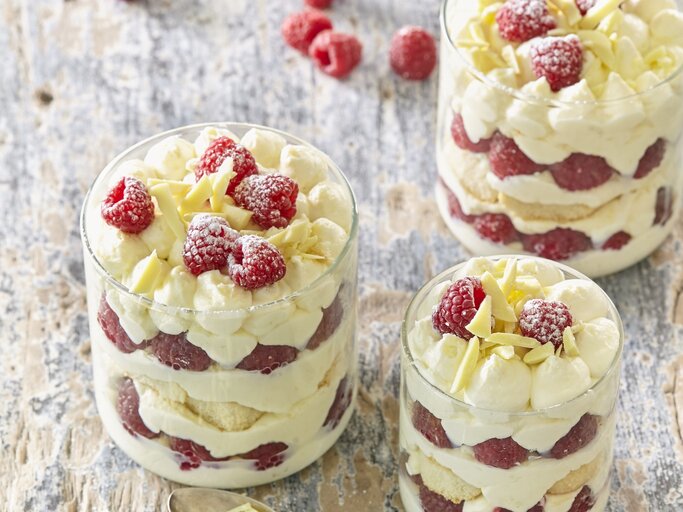 Drei kleine Gläser mit Himbeer-Tiramisu. Das Ganze auf einem hölzernen Untergrund.  | © StockFood / Profimedia