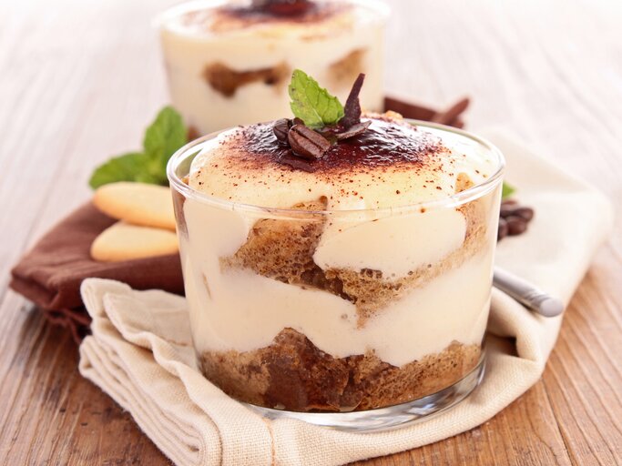 Zwei Gläser mit Biscoff-Tiramisu, bestreut mit Kakaopulver und Kaffeebohnen, geschichtet mit Karamellkeksen. | © Adobe Stock/ M.studio