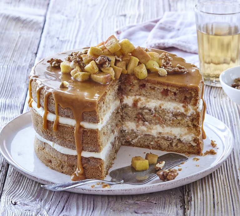 Auf einem Teller steht eine Apfel-Karamell-Schichttorte. Sie ist mit Äpfeln und Nüssen bedeckt.  | © StockFood / Profimedia