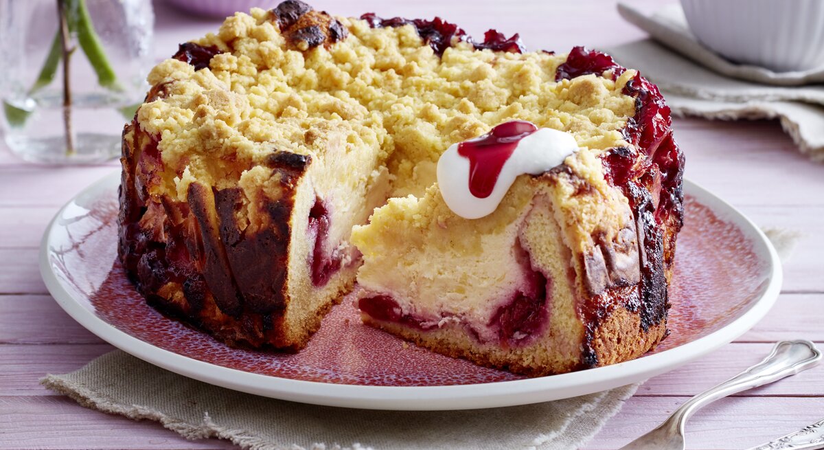 Kirsch-Vanillekuchen mit Streuseln auf Teller serviert.
