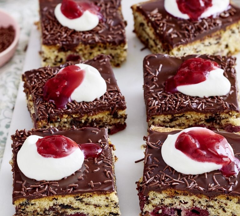 Auf einer Platte liegen mehrere Stücke des Kirsch-Ameisenkuchen. Er ist mit Sahne und roter Grütze verziert. | © EAT CLUB / Isabell Triemer