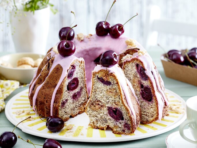 Ein Schmand-Mohnkuchen mit Kirschen auf einem weißen flachen Teller. | © EAT CLUB/Isabell Triemer
