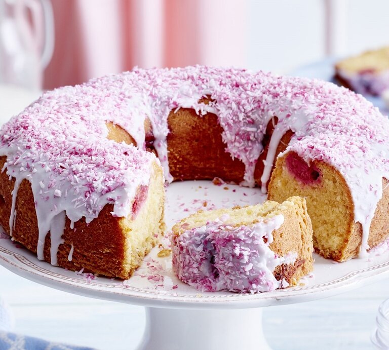 Auf einem Teller liegt ein Kokos-Himbeer-Kuchen. Er ist mit rosa Creme und Haferflocken dekoriert.  | © EAT CLUB / Isabell Triemer