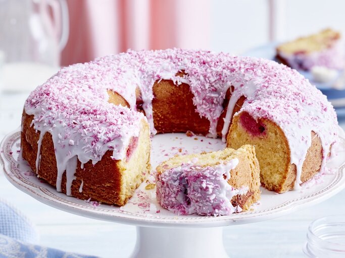 Auf einem Teller liegt ein Kokos-Himbeer-Kuchen. Er ist mit rosa Creme und Haferflocken dekoriert.  | © EAT CLUB / Isabell Triemer