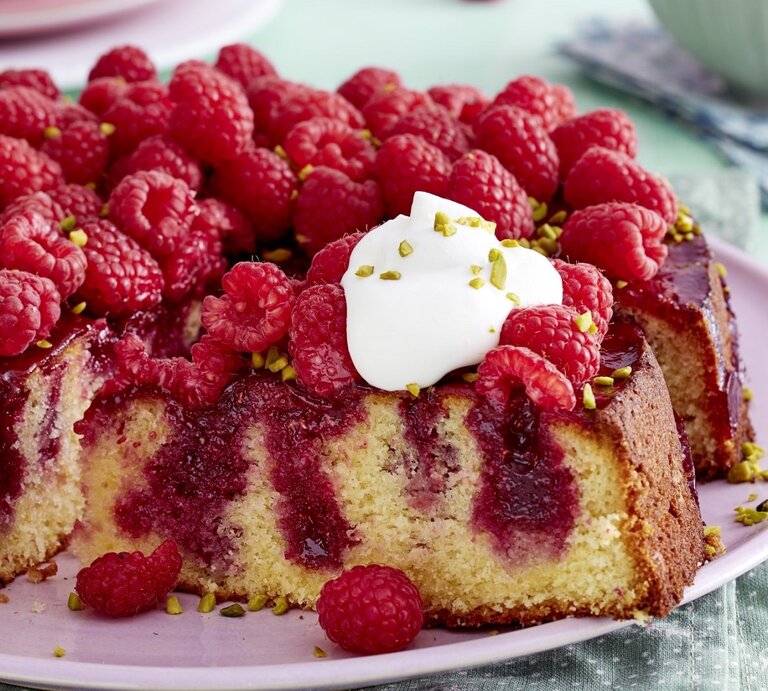 Auf einem pinken Teller liegt ein Himbeer-Zitrus-Kuchen. Er ist mit einem Klecks Schlagsahne bedeckt. | © EAT CLUB / Isabell Triemer