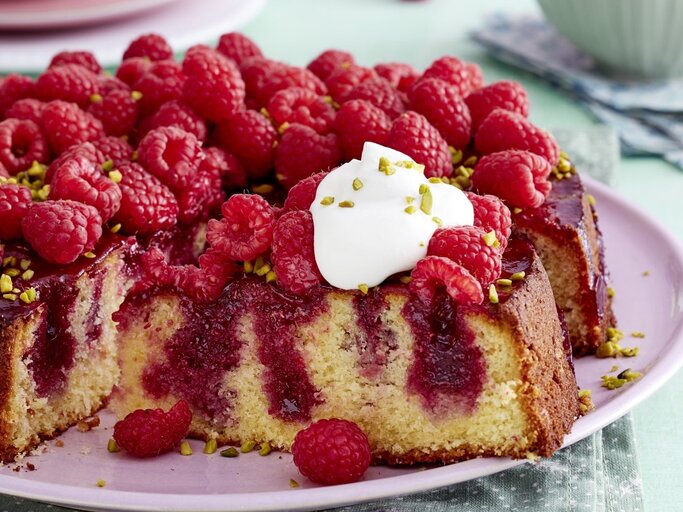 Auf einem pinken Teller liegt ein Himbeer-Zitrus-Kuchen. Er ist mit einem Klecks Schlagsahne bedeckt. | © EAT CLUB / Isabell Triemer