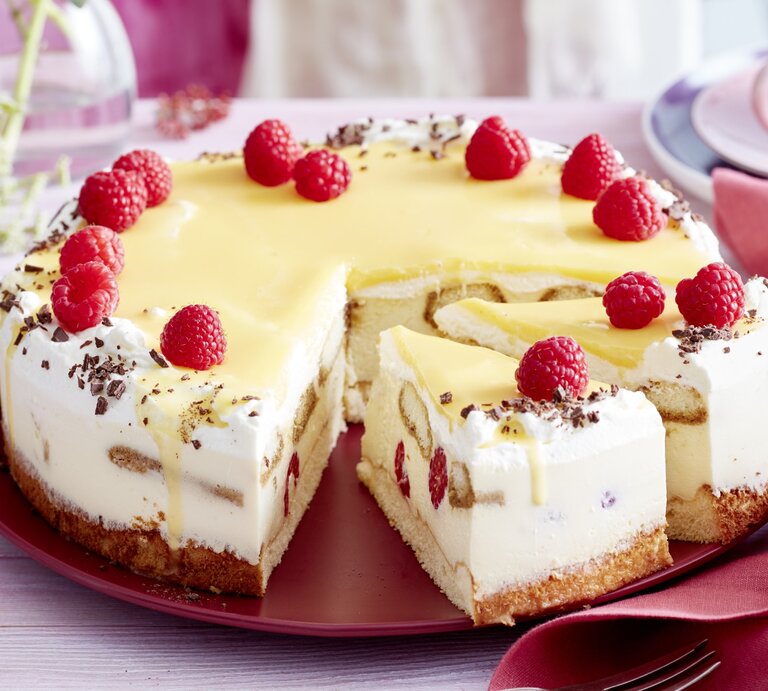 Auf einem Tortenteller steht eine Eierlikör-Himbeer-Tiramisutorte. Sie ist mit Himbeeren und Schokoraspeln dekoriert. | © EAT CLUB / Isabell Triemer