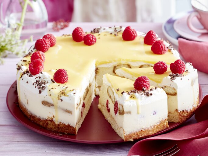 Auf einem Tortenteller steht eine Eierlikör-Himbeer-Tiramisutorte. Sie ist mit Himbeeren und Schokoraspeln dekoriert. | © EAT CLUB / Isabell Triemer