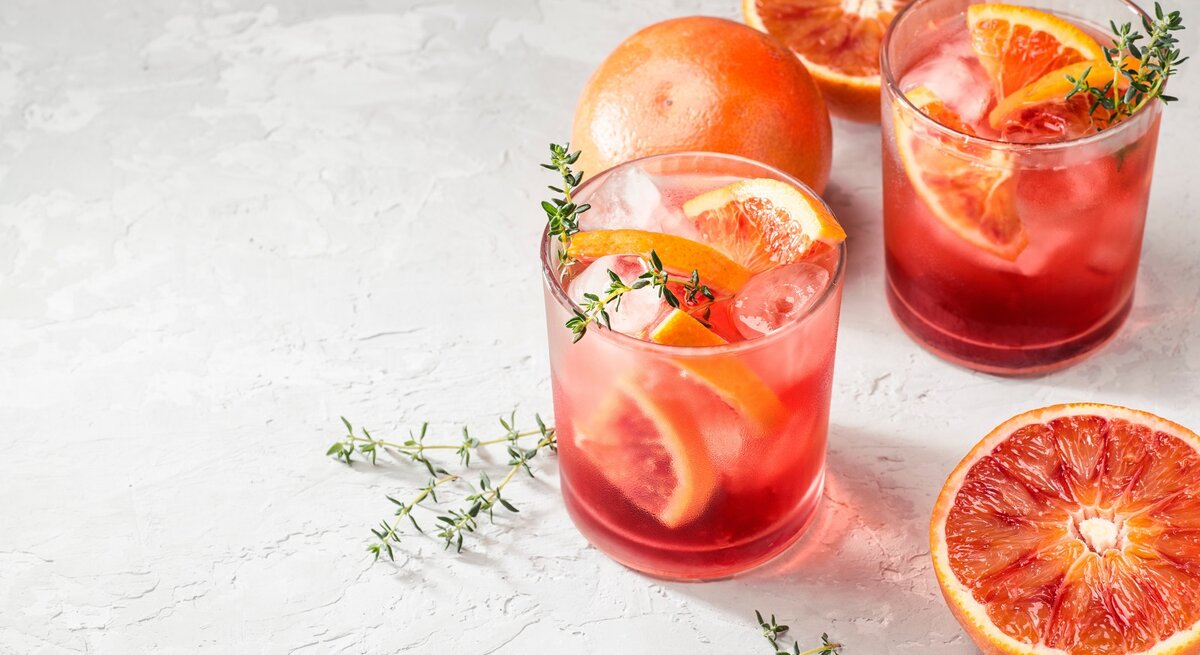 Zwei Gläser mit Campari Spritz auf hellem Untergrund.