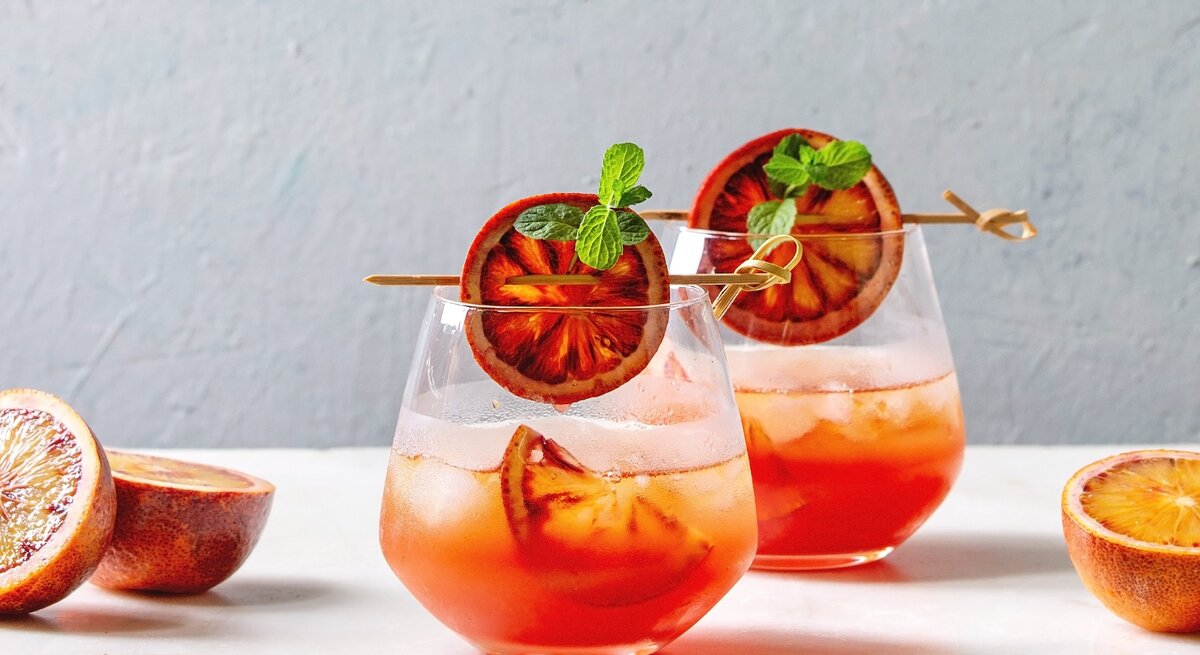 Zwei Gläser Sarti Spritz mit Orangenscheiben dekoriert.