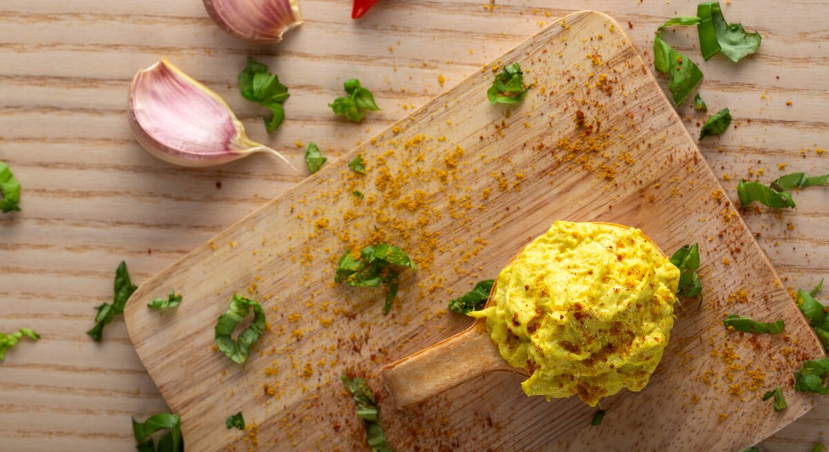 Dattel-Curry-Dip auf Holzbrett, daneben einige Zutaten.