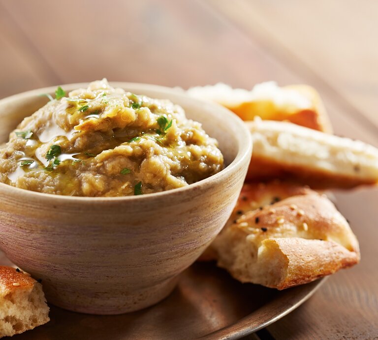Eine Schale Lib el Kousa, ein levantinischer Zucchini-Knoblauch-Dip, auf einem Tablett, darauf außerdem Fladenbrot-Stücke. | © Adobe Stock/raimunda-losantos