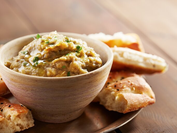 Eine Schale Lib el Kousa, ein levantinischer Zucchini-Knoblauch-Dip, auf einem Tablett, darauf außerdem Fladenbrot-Stücke. | © Adobe Stock/raimunda-losantos