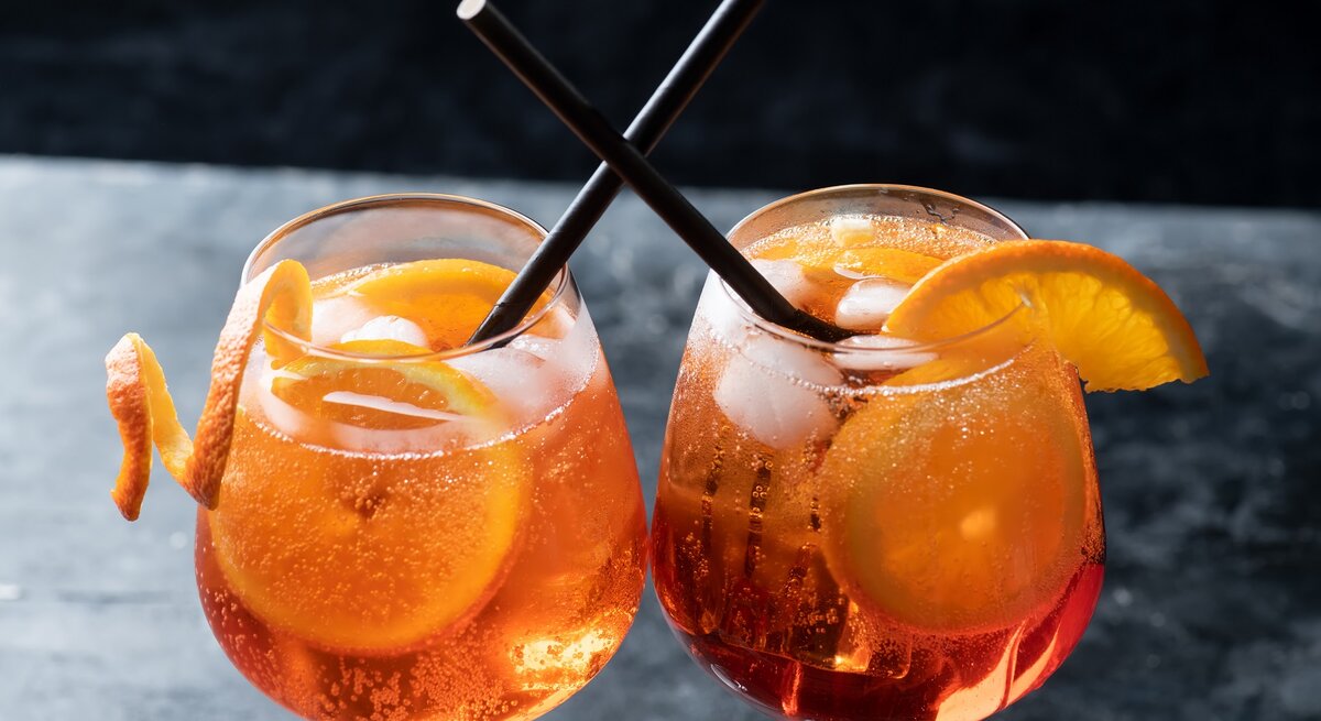Zwei Gläser mit scharfem Aperol auf einem grauen Tisch.