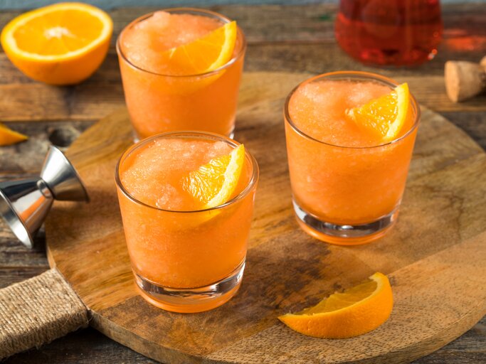 Drei Gläser Frozen Aperol Spritz auf Holzbrett.  | © Getty Images/bhofack2