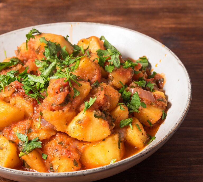 Kartoffelsalat mit Harissa-Dressing und Petersilie in einer Schüssel, daneben eine Gabel. | © Adobe Stock/ Stanislav Ostranitsa
