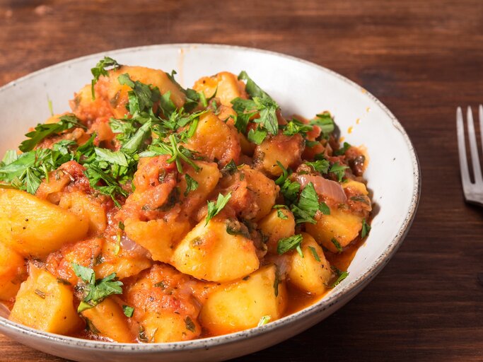 Kartoffelsalat mit Harissa-Dressing und Petersilie in einer Schüssel, daneben eine Gabel. | © Adobe Stock/ Stanislav Ostranitsa