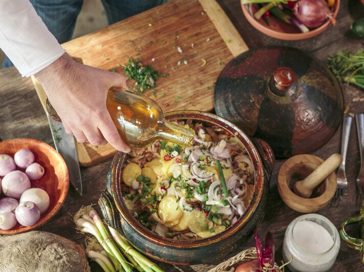 Küchen-Szenario bei der Zubereitung eines Kartoffelsalats. Zutaten in einer Schüssel umgeben von weiteren Zutaten.  | © Getty Images/Lumi Images/Romulic-Stojcic