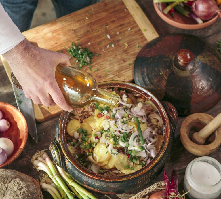 Küchen-Szenario bei der Zubereitung eines Kartoffelsalats. Zutaten in einer Schüssel umgeben von weiteren Zutaten.  | © Getty Images/Lumi Images/Romulic-Stojcic