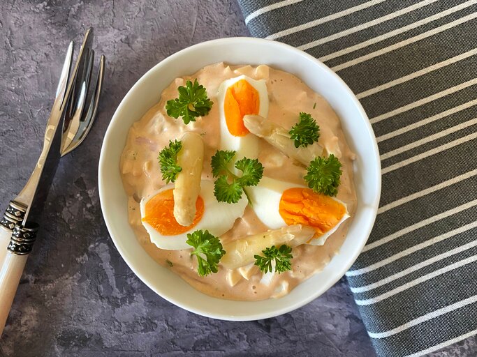 Weiße Schale gefüllt mit Eiersalat mit Spargel auf dunklem Untergrund.  | © Shutterstock/Nagy Julia