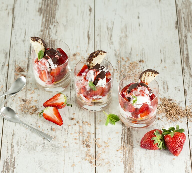 Drei Schalen mit Schokokuss-Erdbeer-Dessert auf weißem Holzuntergrund.  | © Getty Images/Westend61
