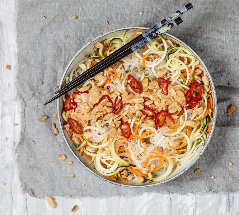 Veganer Glasnudelsalat mit leckerer Erdnusssoße auf einem grauen Tuch. Dazu Stäbchen.  | © Getty Images/ Westend61