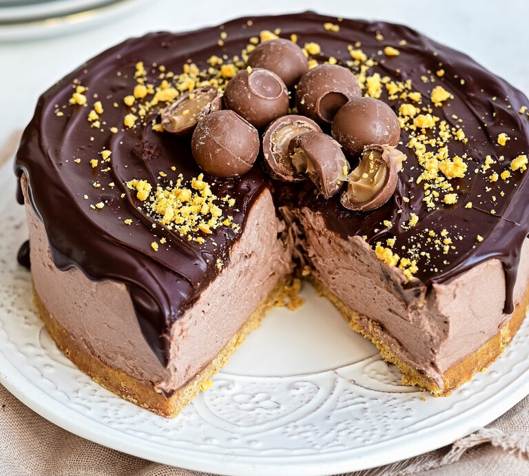 Ein weißer Teller mit einem angeschnittenen Baileys-Käsekuchen mit Schokoglasur auf einem braunen Tischtuch vor einem hellen Hintergrund.  | © StockFood / Parissi, Lucy