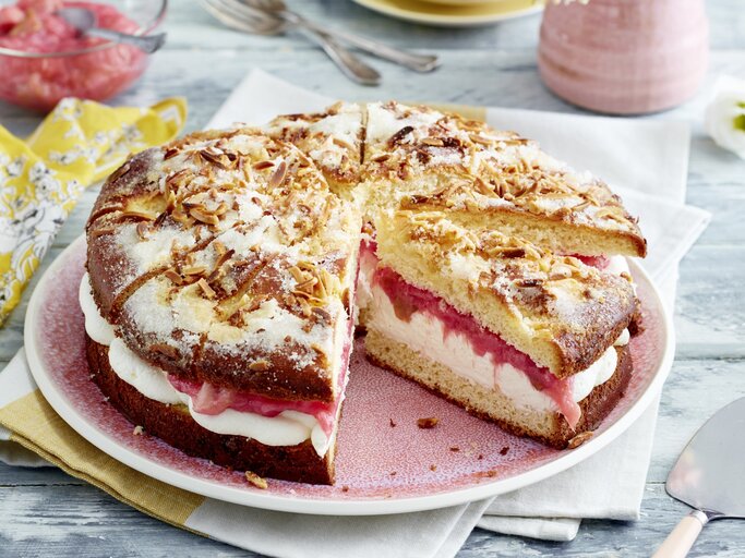 Auf einem Teller ist ein gefüllter Rhabarber-Butterkuchen angerichtet. Er ist mit Puderzucker bestreut. | © EAT CLUB / Isabell Triemer
