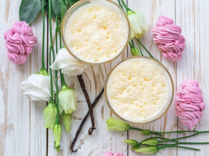 Das Bild zeigt von oben zwei Gläser mit einer Osterbowle mit Eierlikör. Daneben liegen frische Blumen. | © Adobe Stock/dzevoniia