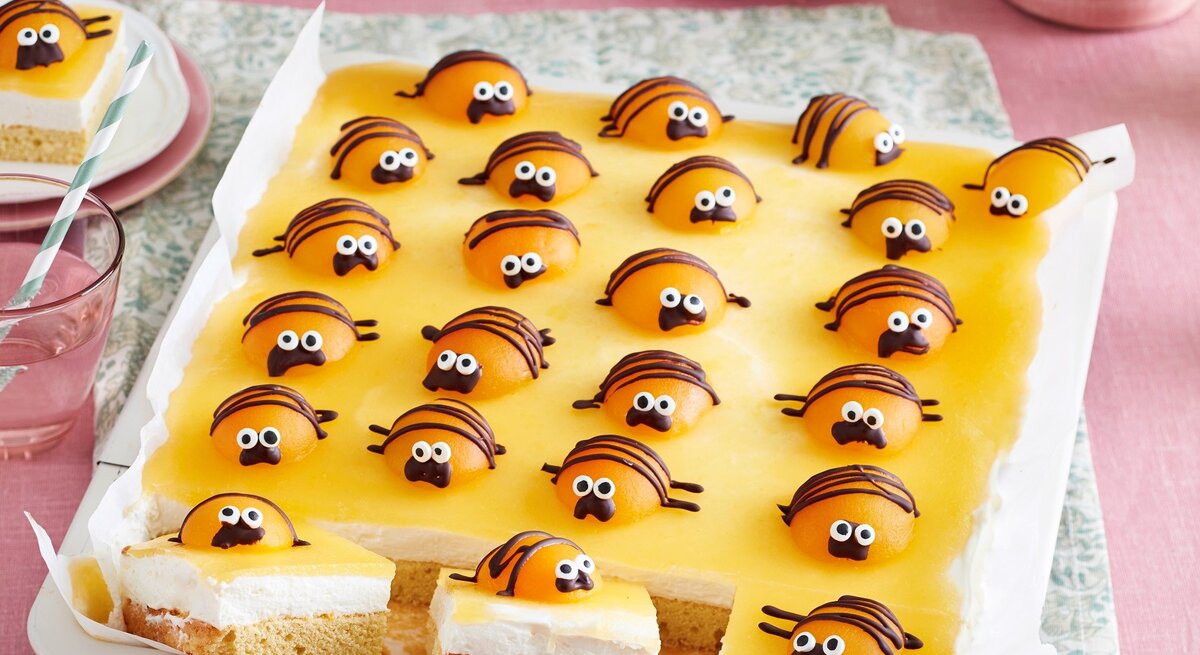 Auf einem Kuchenblech ist ein Käfer-Kuchen angerichtet. Er ist mit kleinen Käfern aus Aprikosen verziert.