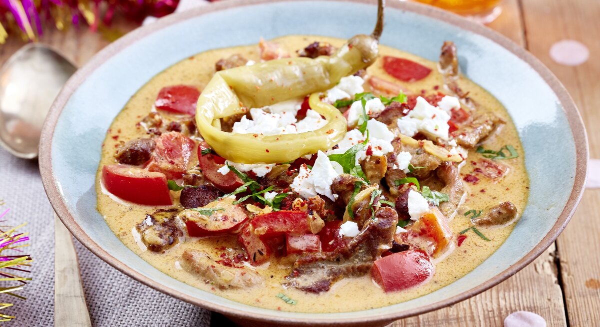 Ein Teller Gyrossuppe mit Feta, drumherum etwas Partydeko.