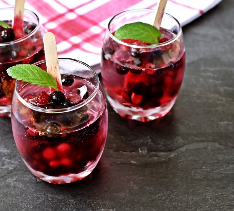 Drei Gläser mit Lillet Hot Berry auf einem grauen Steintisch. | © Shutterstock/Maddas