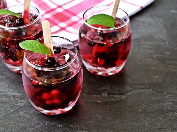 Drei Gläser mit Lillet Hot Berry auf einem grauen Steintisch. | © Shutterstock/Maddas