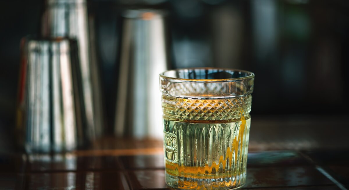 Ein Rührglas gefüllt mit weißem Negroni auf einer Bar. 